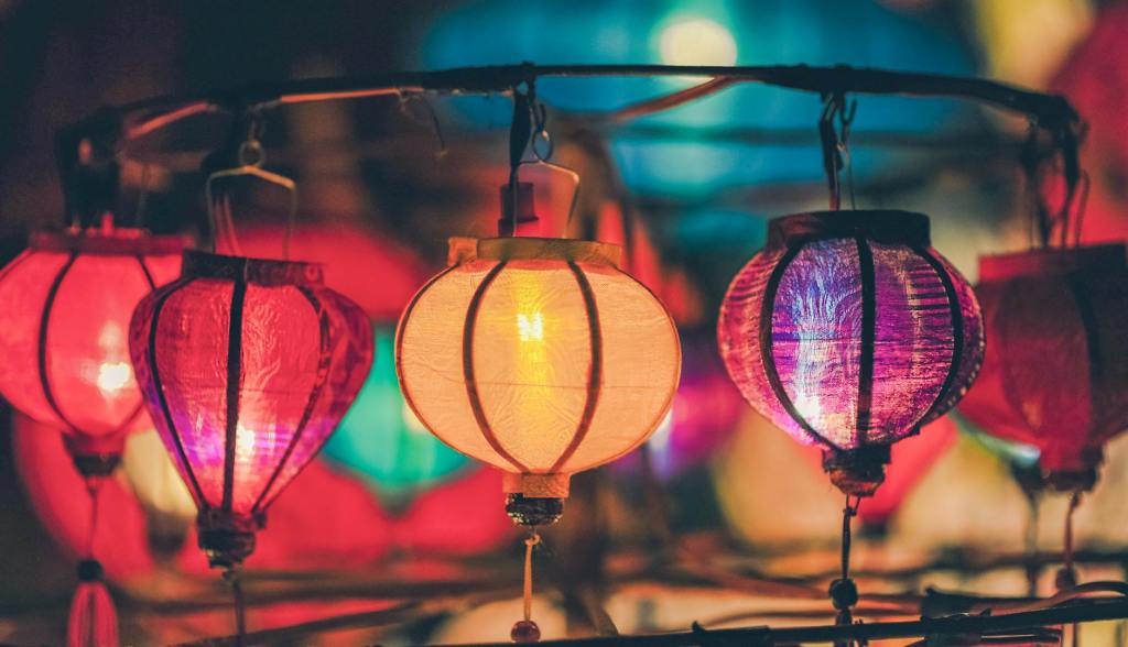 Bright and colourful paper lanterns of red, yellow and purple hang in a circle.